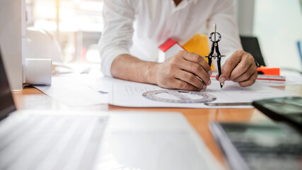 Male architect or engineer working for designing, drafting work plans and building house.