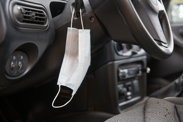 The medical mask hangs on the car control panel. The concept of implementing the rules for...