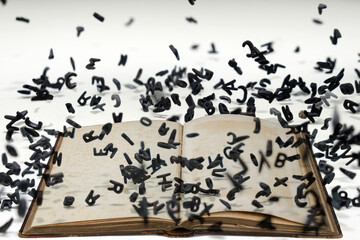 Letters of the alphabet in levitation in the air over the open book