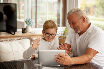 Grandson and grandfather speaking through video chat app using tablet.