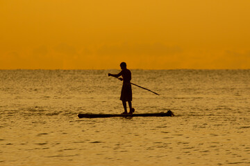 Fototapeta na wymiar silhouette of a man at sunset in the sea on a board with a paddle