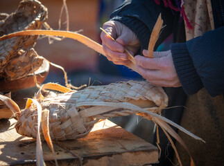 The woman weaves bast shoes.