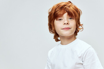 Portrait of red-haired boy cropped view white t-shirt smile studio 