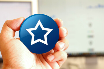 Star icon blue round button holding by hand infront of workspace background