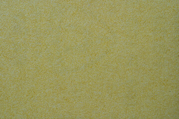 Yellow ocher stucco texture on exterior wall with fine grains. Yellow sandpaper background macro