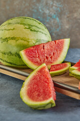 Mini Watermelon with sliced wedges on a wooden stand on a blue background