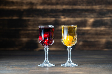 Homemade tincture of red cherry and yellow cherry plum in a wine crystal glasses on wooden background, Ukraine