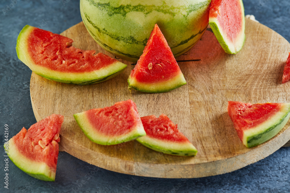 Poster Mini Watermelon with sliced wedges on a round wooden stand on a blue background