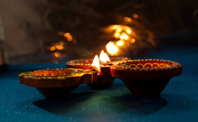 Happy Diwali - Colorful clay diya lamps lit during diwali celebration with glittering bokeh