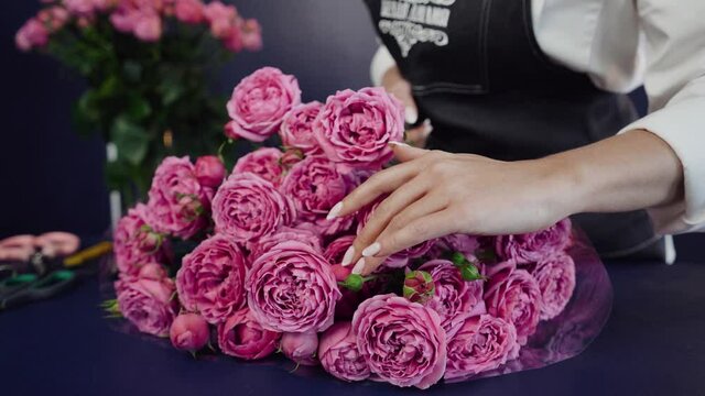 Professional florist assembles a Wedding Bouquet. Young florist assembles a perfect pink rose bouquet. Her flowers are wonderful, the colors are so beautiful