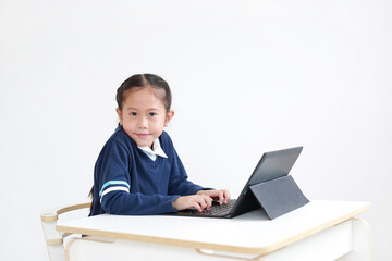 Portrait asian little child girl in school uniform using laptop on table isolated on white background with looking camera, Studio shot