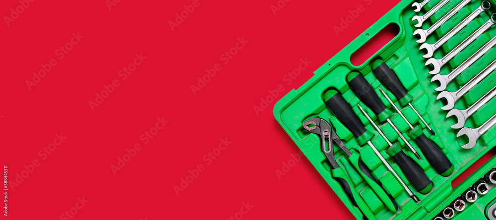 Wall mural Green set of construction tools: wrenches, adjustable pliers, screwdriver and so on on a red background. Banner with place for text for a hardware store. Metal hardware for professional repair or DIY