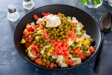 Step by step preparation of salad with red fish and vegetables, step 6 - adding canned green peas, mayonnaise and salt to the salad, selective focus, horizontal