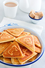 Traditional Russian cookies, cooked on a plate in the form with prints, without baking in an enameled white bowl, selective focus