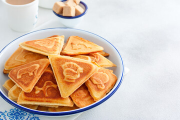 Traditional Russian cookies, cooked on a plate in the form with prints, without baking in an enameled white bowl, selective focus, copy space