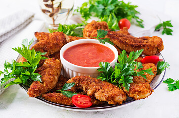 Breaded mini chicken fillets served with tomato sauce. American food. Chicken nuggets with parsley.