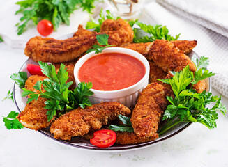 Breaded mini chicken fillets served with tomato sauce. American food. Chicken nuggets with parsley.