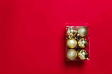 Golden Christmas balls-toys are packed in a transparent plastic box. Preparing for the Christmas holidays. Banner for a store selling Christmas decorations. Post-holiday cleaning