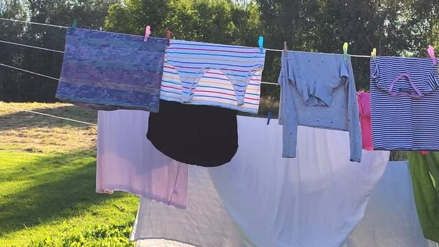 Colorful cotton laundry hanging on the rope outdoors. The process of air drying clothes