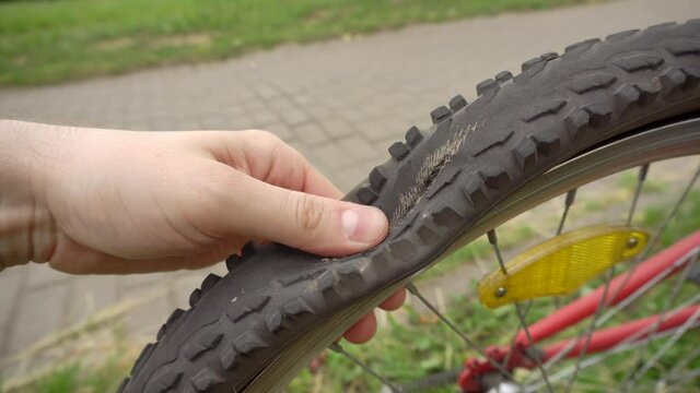 A cyclist rolls a bicycle with a flat, punctured wheel, close-up. Punched wheel tube, industry
