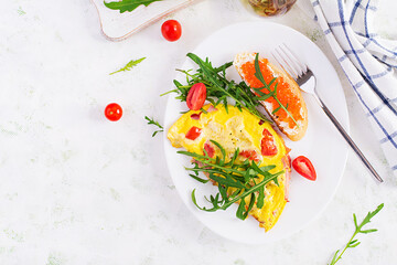 Omelette with tomatoes, cheese, ham and sandwich wich red cavier on plate.  Frittata - italian omelet. Top view, overhead, copy space