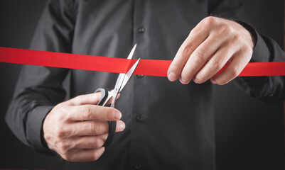 Man cutting red ribbon with a scissors.