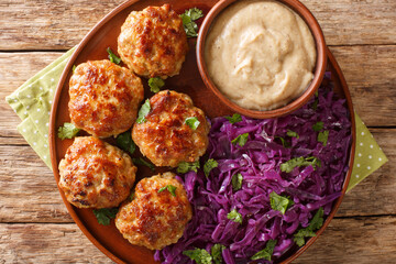 Fried Danish meatballs with hot stewed red cabbage and sauce close-up in a plate on the table. horizontal top view from above