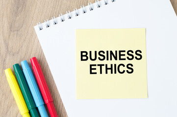 Business Ethics inscription on a notebook on an office table, next to lie colored markers.