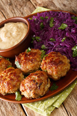 Danish meatballs frikadeller served with stewed red cabbage garnish close-up in a plate on the table. vertical