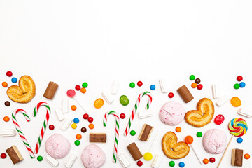 Various colored sweets on a white background. Lollipops, caramel, candy canes, marshmallows, chocolate, cookies top view