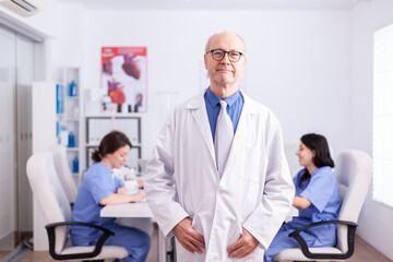 Fototapeta premium Elderly aged expert doctor in hospital conference room wearing lab coat.