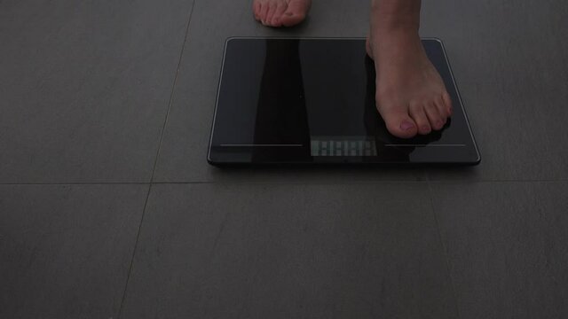 Adult woman measuring herself on a scale put weight.