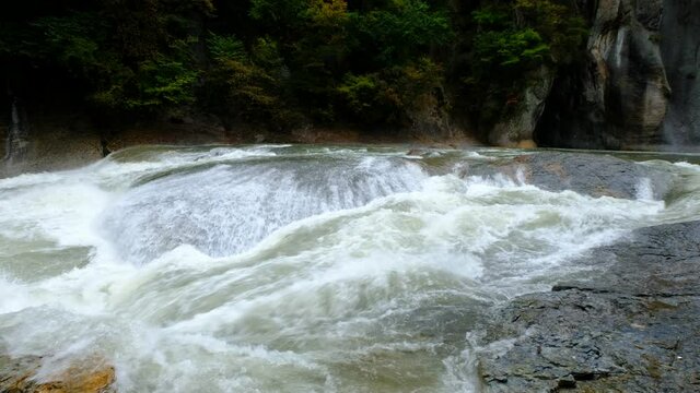 A large water stream that flows noisily in a huge rocky environment, 4K resolution, next to Numata, near Nikko National Park, Japan.