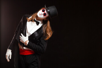 Portrait of male mime artist performing, isolated on black background. Man is standing straight tilt his head with his hand on the stomach