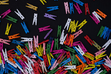 Colored wooden clothes pegs on black background, colorful banner