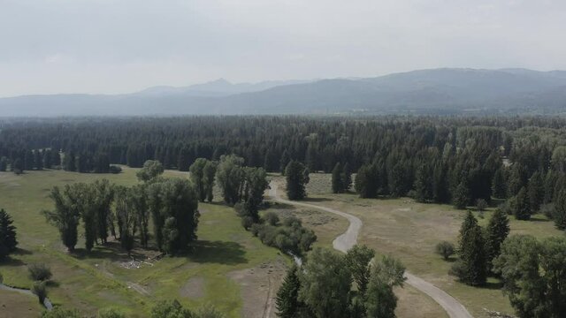 Green Landscape of Wyoming USA.  Aerial View of Green Forest and Local Restricted Road in Valley Under Grand Tetons Near Jackson Hole by Harrison Ford's Property