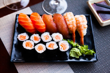 Appetizing sushi set from salmon makizushi and nigirizushi with various toppings served on black plate with wasabi and soy sauce. Popular Japanese dish