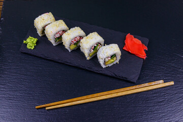 Uramaki sushi rolls with surimi on a black slate
