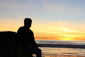 silhouette of a person sitting on the beach