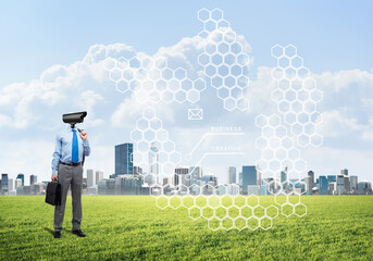 Camera headed man standing on green grass against modern cityscape