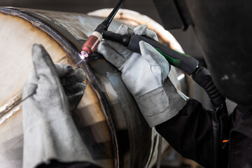 Close up of industrial worker hands welding metal structure at workshop.	