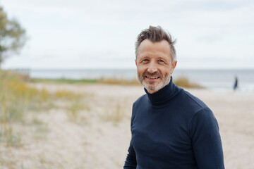 Smiling friendly senior man at the beach