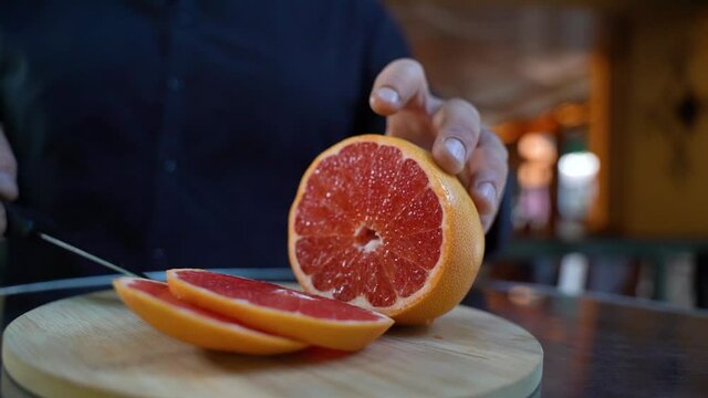 bartender preparing a cocktail, cutting grapefruit