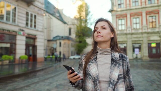Woman walking down an old street and using smartphone