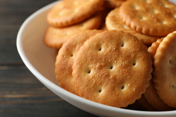 Bowl with tasty cracker biscuits on wooden background