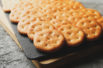 Board with cracker biscuits on gray background