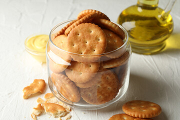 Glass jar with crackers, sauce and oil on white table
