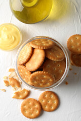 Glass jar with crackers, sauce and oil on white table