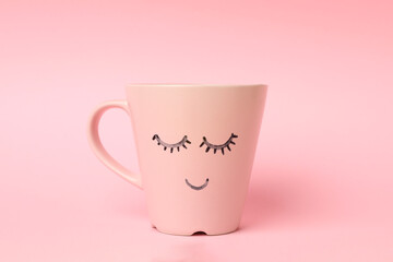 Cup with happy face on pink background