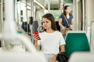 Fototapeta premium Woman using mobile phone in the cabin of a bus or tram. High quality photo